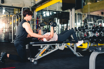 Young Asian trainer is introducing a dumbbell For Asian girls In the fitness center This pose will...