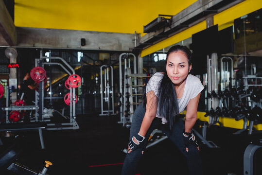 Close up image of beautiful Asian women Standing resting after a workout in the fitness center The backdrop is various equipment in the gym. Concept: Sporty girl in the gym.