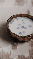 Milk and blue flowers in a bronze bowl.