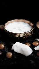 Milk and blue flowers in a bronze bowl on a dark background. 