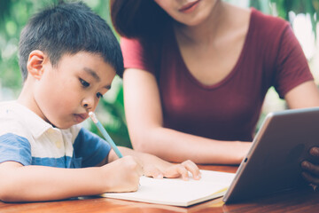 Fototapeta premium Son using digital tablet computer for study and learn to internet online with mother together, education from home, family recreation, mom teach boy and homework with technology, lifestyle concept.