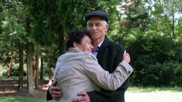 Loving old couple walking in the park. Grandparents laugh and hug. Beautiful old man and happy old woman.
