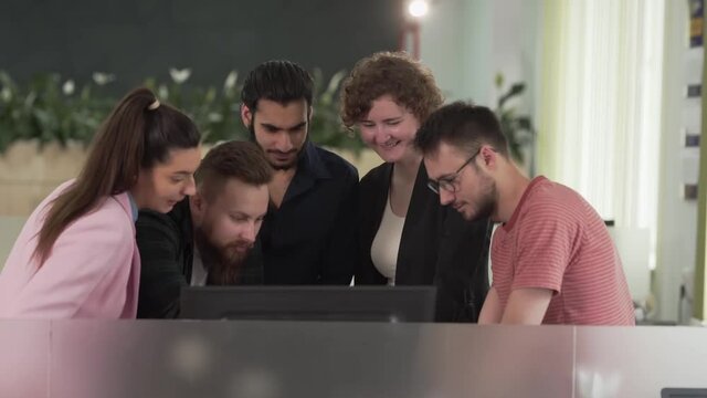 group of young office workers working together at the computer