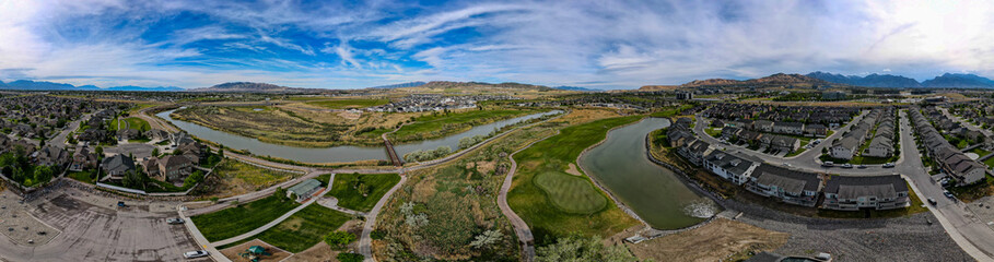 Panoramic aerial view of a river running through a suburb and golf course