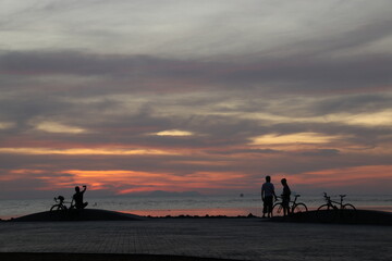 Silhouette of a cyclist on the beach at sunrise.