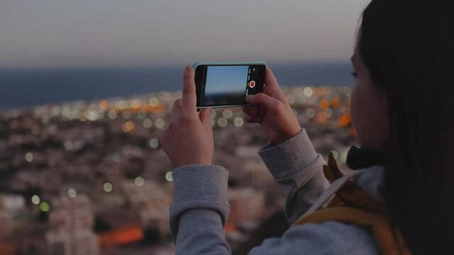 Woman take picture of the sea by smartphone in the evening. Woman stay on top of the mountain and looking Into Horizon, 4k