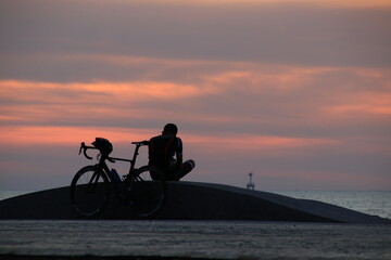 Silhouette of a cyclist on the beach at sunrise.