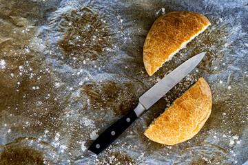 cut bread with knife on used baking paper and flour, cooking and baking concept background