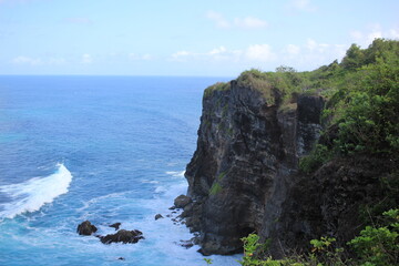 Fototapeta na wymiar A large cliff i overlooking the endless blue ocean on a sunny day in a tropical location