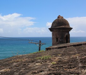 Stone watchtower of a stone fort overlooking the blue ocean with blue sky above