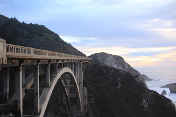 Beautiful bridge in California with mountains and cloudy but bright sky in the background 