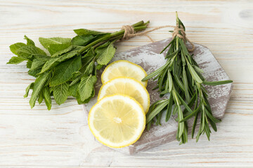 Lemon, mint and rosemary, ingredients for herbal tea and sauce, herbs and lemon on the table
