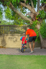 Asian father and children, teach to ride bicycles, spend time at home, Dad teach son to ride bike, father's day concept