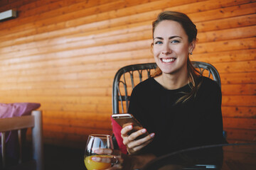Cheerful female student is using cell telephone during rest after lectures