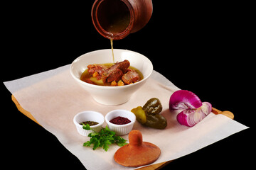 Sliced meat with chick pea. Boiled meat is filled with broth. Black background