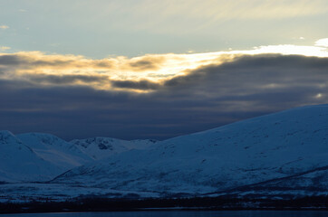 golden sunshine on clouds over snowy mountain