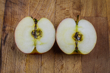 Two half of a red white apple on a wooden background close up