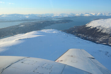 Fototapeta na wymiar snowy mountain peak and tromsoe city island in the background aerial shot