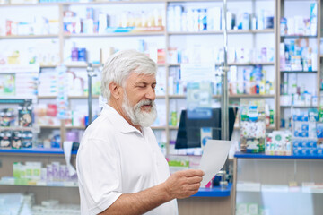 Fototapeta na wymiar Senior man reading prescription in apothecary.