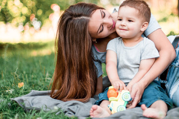 Mother with little son spend time together in green park.