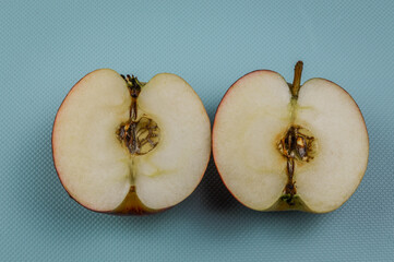 Two half of a red apple on a light blue background close up