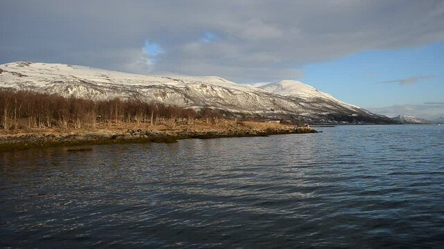 sandy beach bay with snowy mountain background in northern Norway