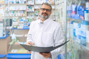 Specialist standing in drugstore, holding folder.