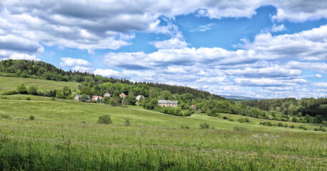 Fototapeta na wymiar Small village with few houses on hillside with cloudy sky