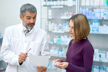 Pharmacist explaining instruction of pills to woman.