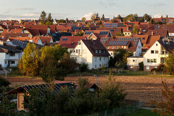 Fototapeta na wymiar Horizontal wide view over an agricultural field, and houses with red roofs in the German village of Malmsheim, in the background. Small town in the southern state of Baden-Württemberg, during daytime