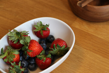 Close up wooden table with strawberry and blueberry  in white bowl