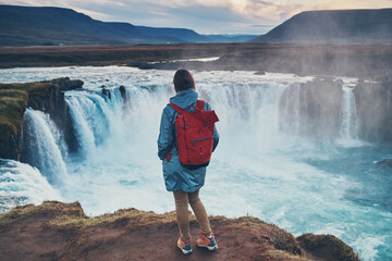 The girl looks at the Godafoss waterfall at sunset. Iceland.