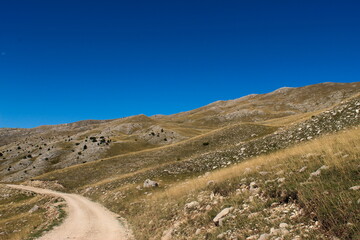 Old road on the mountain Bjelasnica, a landscape with lots of stones and dry grass. Bjelasnica Mountain, Bosnia and Herzegovina.