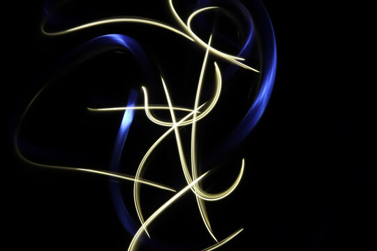 Abstract flower background with long exposure light painting photography, curvy lines and vibrant metallic neon white and blue against a black background.