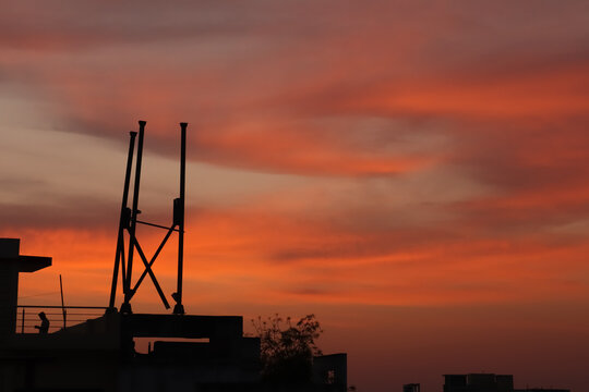 Silhouette of a cell phone tower under construction on a tall building with colorful evening sky after sunset looks like the Northern Lights or Aurora borealis. Copy space. - Powered by Adobe
