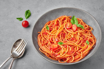 Tomato spaghetti in gray bowl on concrete background. Tomato sauce pasta is classic italian cuisine dish. Popular italian food