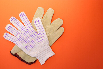 Different types of construction gloves on a bright orange background. Means of protection and security. Copy space for text. Concept for advertising construction.