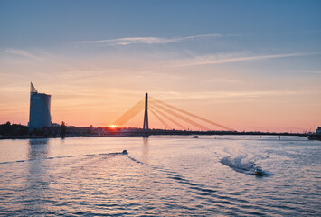 The sun sets behind the bridge on the river Daugava. Riga, Latvia. Sunset.
