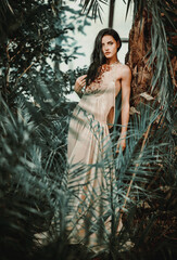 Gorgeous young woman wearing long evening fashionable dress posing in forest. Beauty and fashion concept