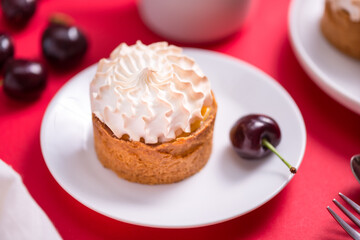 Sweet tart with cream and cherry on red table