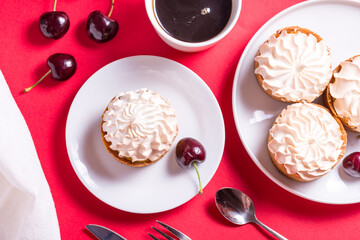 Sweet tart with cream and cherry on red table
