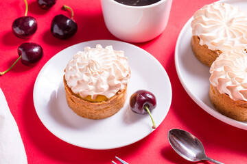 Sweet tart with cream and cherry on red table