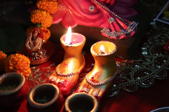 Beautifully decorated oil lamps in the shape of the feet of goddess laxmi illuminating the decoration around it by burning on the occasion of Diwali in India. They are commonly known as lakshmi diyas.
