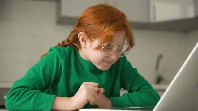 Cute schoolgirl in eyeglasses checking her marks in online register, slow-motion