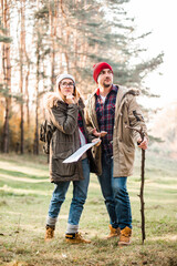 Travel couple with map, compass and backpack in the forest. Freedom and active travel concept.