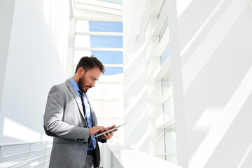 Fototapeta premium Half length portrait of rich businessman holding portable digital tablet during work break in hallway