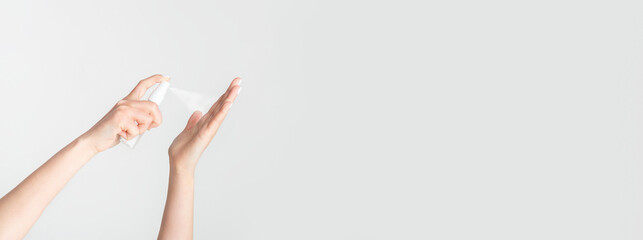 Closeup view of young female spraying antiseptic onto her hands against white background, copy space