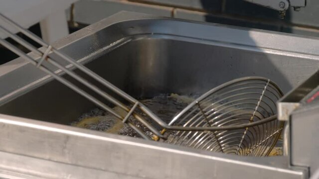 Slow motion: chef cooking homemade crunchy churros in boiling oil at summer outdoor food market - close up view. Traditional spanich cuisine, catering, cookery, gastronomy and street food concept