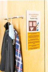 Warning note in georgian language with hanging clothes in mens changing room. Concept of safety regulations in stores while shopping. Tbilisi. Georgia. 02.06.2020