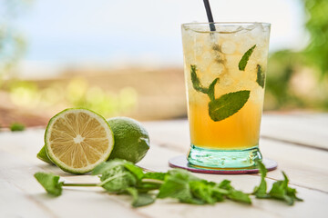 Mojito ready to drink with the beach in the background. Drinking concept for summer.